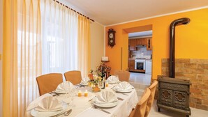 A dining room with a table set for four, a clock on the wall, and a kitchen in the background. - Awesome home in Gajana (Gajana)