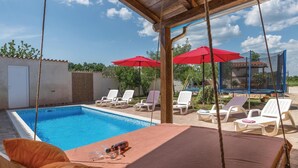 A pool area with lounge chairs, red umbrellas, and a covered seating area. - Awesome home in Gajana (Gajana)