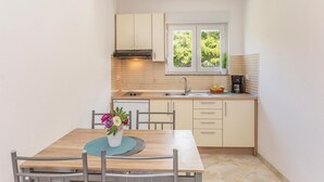 Cocina compacta con ventana, un lavamanos, estufa y comedor con mesa y sillas.