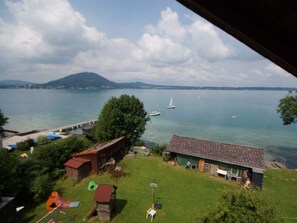A lakeside property with a grassy yard, a small shed, and a house with a sloped roof. - Sparer Normal - Gasthof zur Landeroith (Weyregg am Attersee)