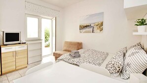 A modern bedroom with a bed, a TV, a sofa, and a painting on the wall. - Studio with air conditioning and terrace (Baška)