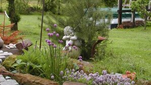 Un jardín con una estatua, diversas plantas y un sendero de piedra.