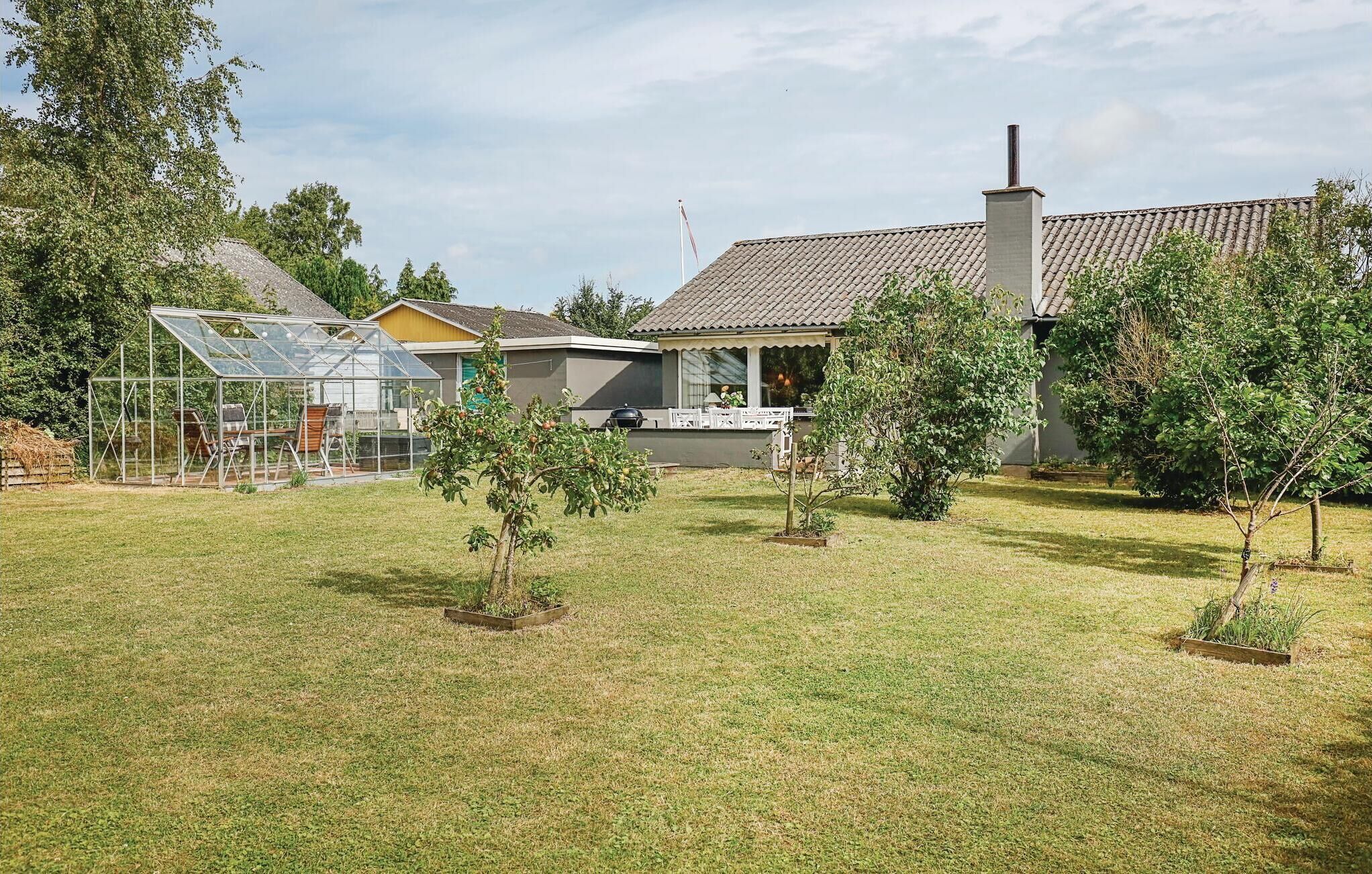 A residential property with a greenhouse, a small house, and a garden with young trees.