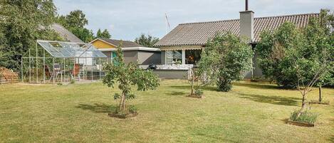 A residential property with a greenhouse, a small house, and a garden with young trees.