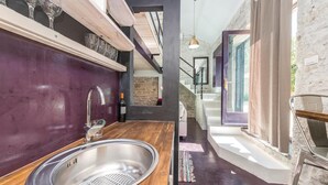 Une cuisine moderne avec un plan de travail en bois, un évier en acier inoxydable et une bouteille de vin.