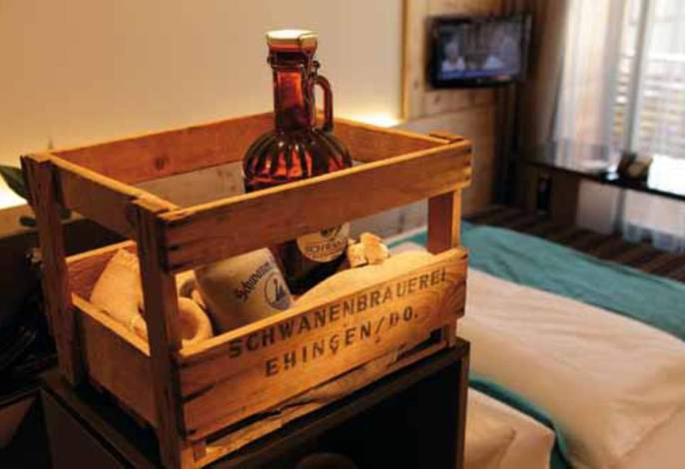 A wooden crate with a bottle and a pillow labeled "SCHWANENBRAUEREI EHINGEN/DO."