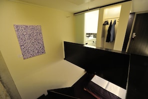 Une chambre d’hôtel avec un lit, une salle de bain avec un miroir et une œuvre d’art accrochée au mur.
