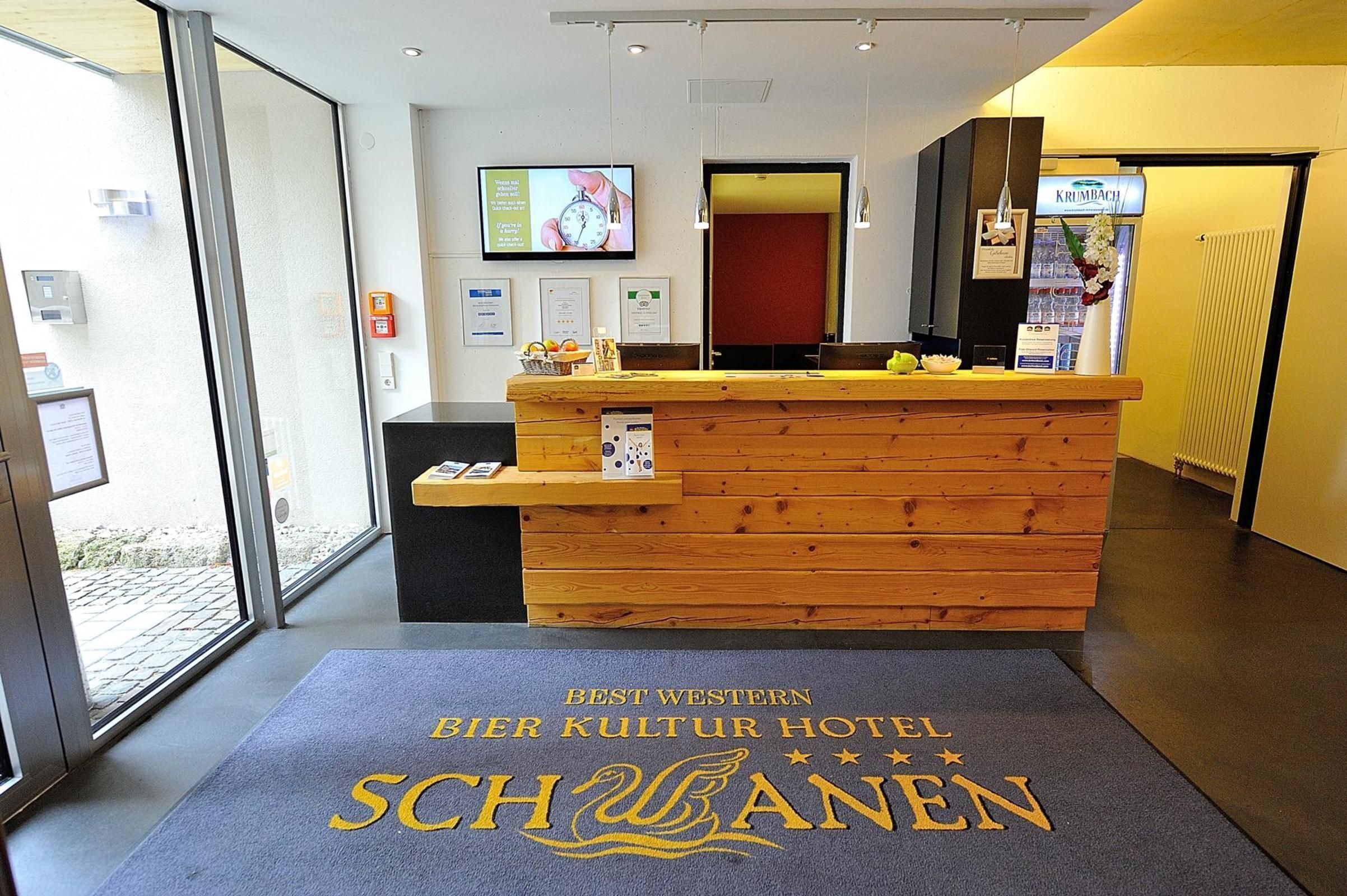 Una recepción con detalles de madera, un reloj digital y un cartel que dice 'Best Western Bier Kultur Hotel Schöningen'.