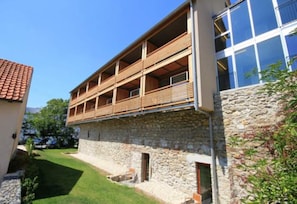 Un immeuble à plusieurs étages, doté d’une façade en pierre et de balcons en bois.