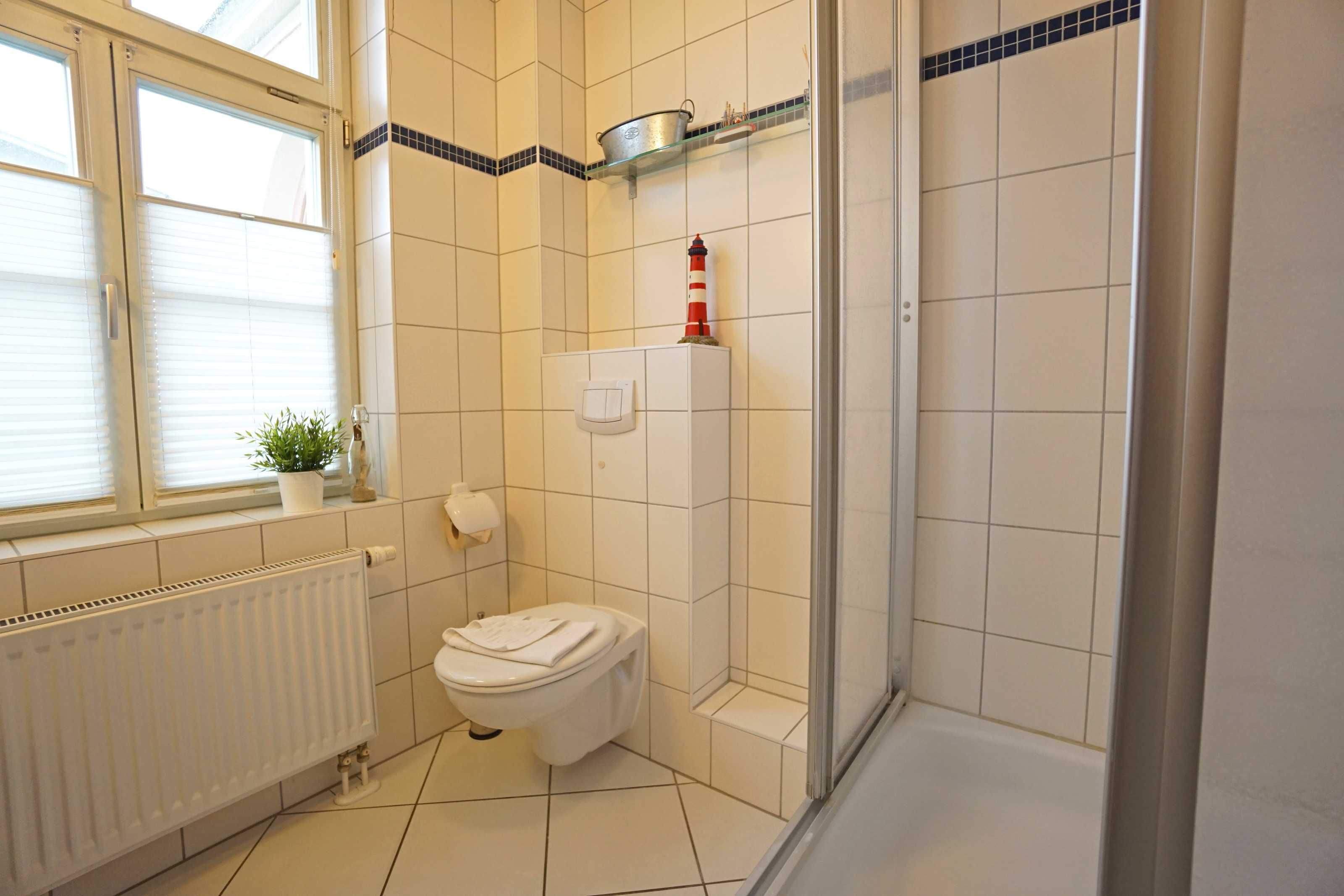 Une salle de bain équipée de toilettes, d’un radiateur, d’une douche et d’une fenêtre.