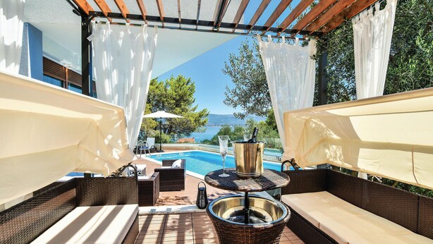 Un área de estar al aire libre con mobiliario de mimbre, una piscina y vistas al mar.