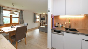 Eine moderne Küche mit Geschirrspüler, ein Essbereich mit Tisch und Stühlen sowie ein Wohnbereich mit Sofa und Fernseher.