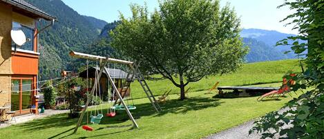 Une maison avec une balançoire, un arbre et une vue sur les montagnes.