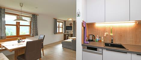 A modern kitchen with a dishwasher, a dining area with a table and chairs, and a living area with a sofa and a TV.