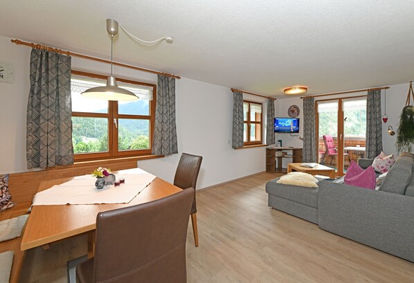 A living room with a dining table, sofa, and TV.
