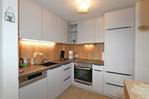 A compact kitchen with a dishwasher, oven, and a coffee maker.