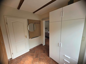 A hallway with a white door, a mirror, and a wardrobe.