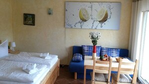 Habitación de hotel con cama, sofá azul, mesa de comedor con sillas y un cuadro en la pared.