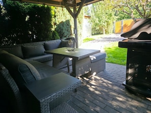 Un patio exterior con un sofá, una mesa y una parrilla.