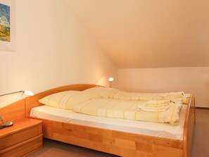 Una cama individual con estructura de madera, una mesita de noche con lámpara, y un cuadro colgado en la pared.
