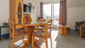 Ein Essbereich mit Holztisch und -stühlen, einem Fernseher und Blick ins Freie.