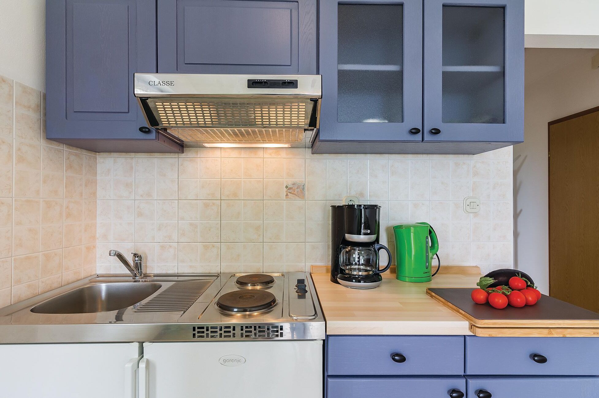 Een keuken met een fornuis, spoelbak en kasten.