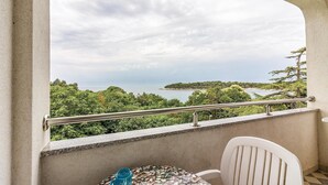 Ein Balkon mit Blick auf eine Küstenlandschaft, inklusive Tisch mit Stühlen und Geländer.
