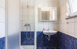 Une salle de bain avec une douche, un lavabo et un miroir.