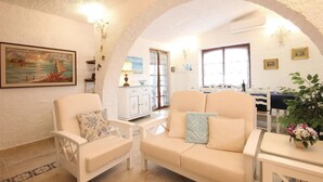Una sala acogedora con un sofá, sillones, una mesa de comedor y una cocina al fondo.