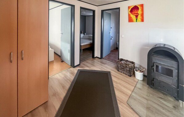 A modern interior with a wooden wardrobe, a fireplace, and a hallway leading to a bedroom with a bed and a nightstand. - 2 bedroom nice home in Oberelbert (Oberelbert)