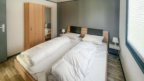 A double bed with white bedding, a wooden wardrobe, a bedside table with a lamp, and a window with blinds. - 2 bedroom nice home in Oberelbert (Oberelbert)
