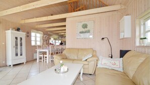 A cozy room with a wooden ceiling, a dining area with a white table and chairs, a beige sofa, and a cabinet. - 2 bedroom amazing home in Væggerløse (Væggerløse)