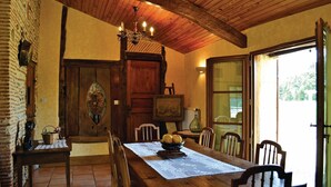 Un coin repas rustique avec une table en bois, des chaises et un lustre.