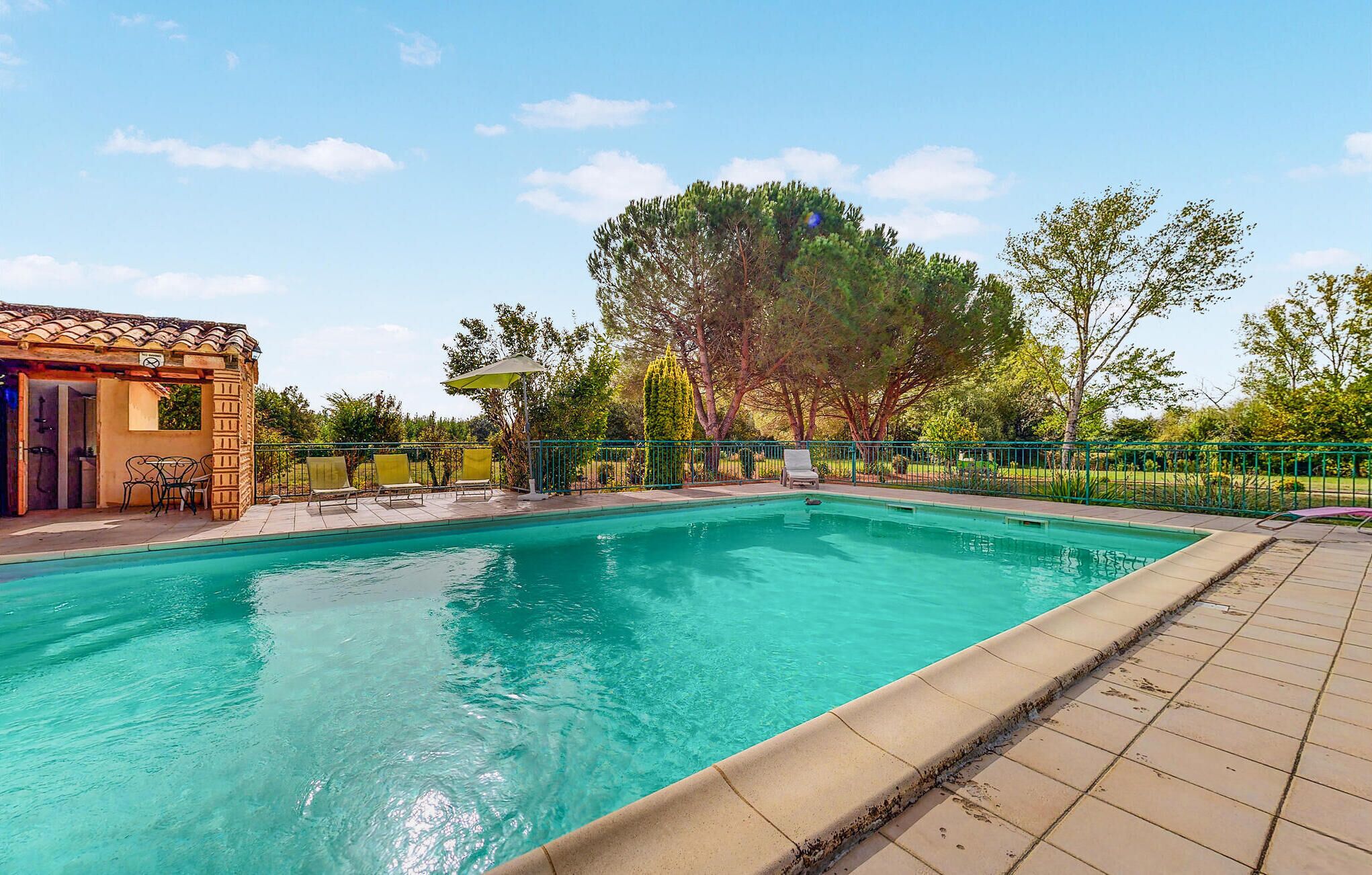 A swimming pool with a tiled deck, a covered seating area, and a pergola.