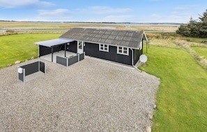 A single-story building with a gravel driveway, a covered outdoor seating area, and a satellite dish. - Nice home in Thyholm with WiFi (Thyholm)