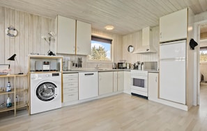 A modern kitchen with white cabinetry, a built-in washing machine, a stove, and a refrigerator. - Nice home in Thyholm with WiFi (Thyholm)