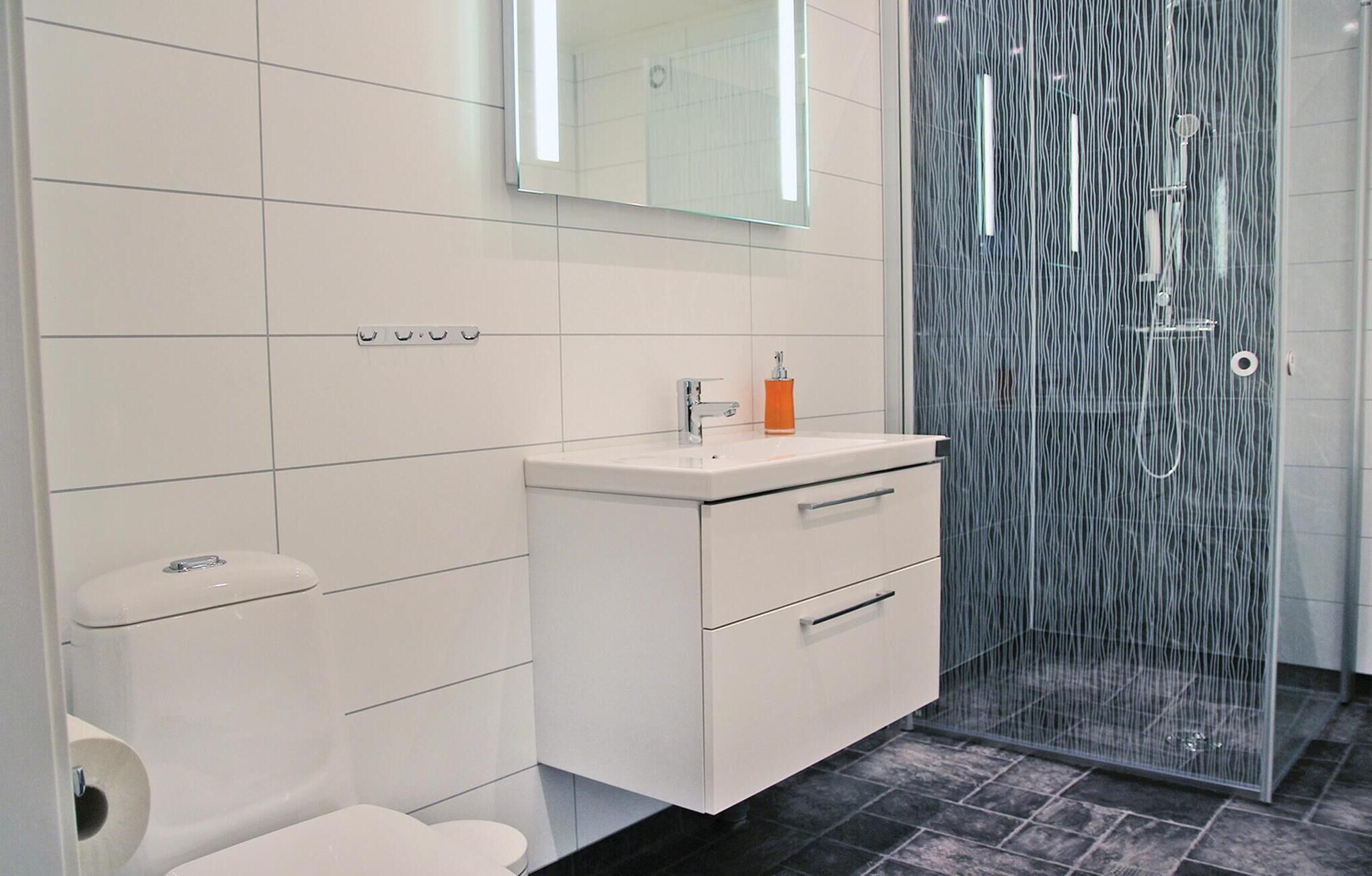 A modern bathroom with a white vanity, a glass shower enclosure, and a toilet.