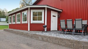 Un edificio rojo con un patio techado, una parrilla y mobiliario para exteriores.
