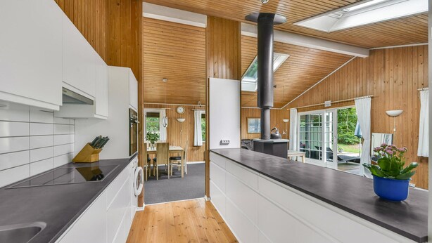 A modern kitchen with wooden accents, a central island, and a view to the outdoors.