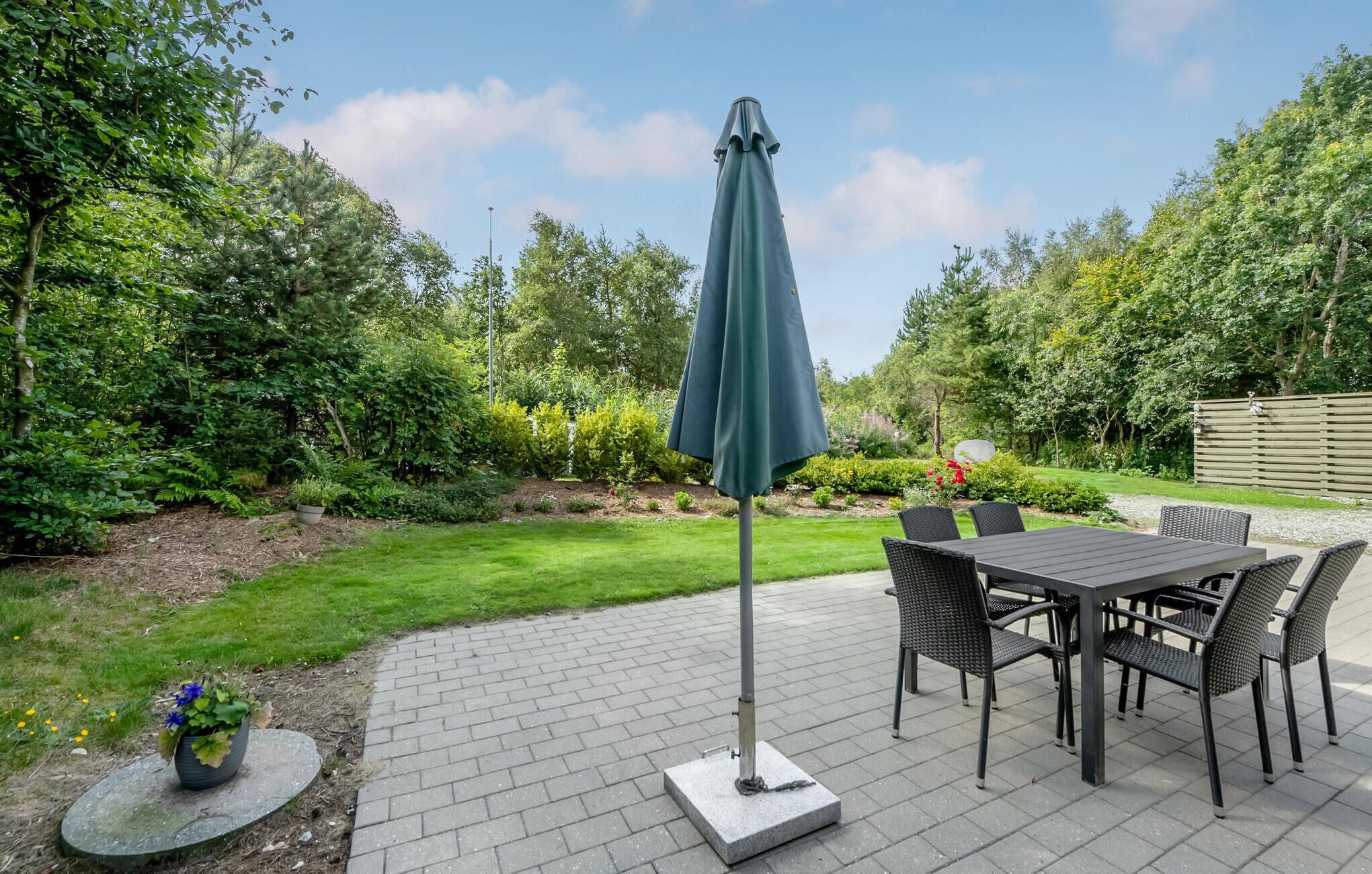 A patio area with a table and chairs, a potted plant, and a green umbrella.