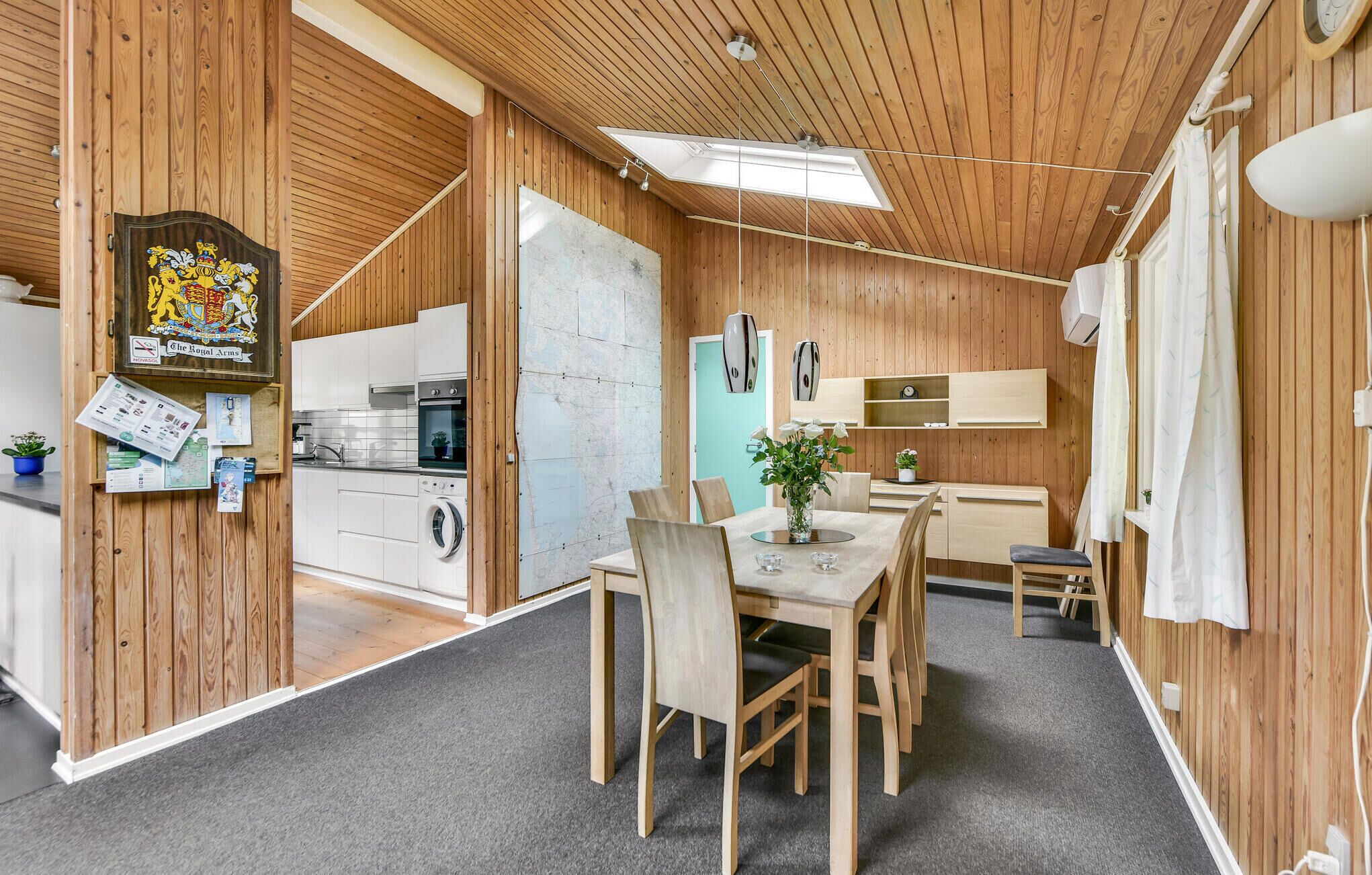 A compact kitchen with wooden walls, a dining area with a table and chairs, and a small seating area with a sofa.