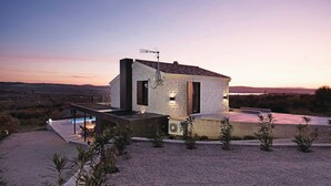 Una casa moderna amb façana de pedra, antena parabòlica i zona de piscina.