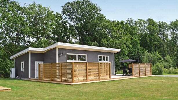 A small, single-story building with a grey exterior and white trim, featuring a covered patio area with outdoor seating. - Nice home in Borgholm with WiFi (Borgholm)