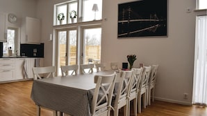 A dining area with a checkered tablecloth, white chairs, and a large window with a view of a bridge at night. - Nice home in Borgholm with WiFi (Borgholm)