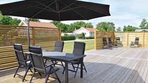 An outdoor patio with a table and chairs, a large umbrella, and a barbecue grill. - Nice home in Borgholm with WiFi (Borgholm)