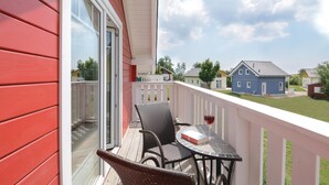 A balcony with wicker chairs, a small table, and a glass of red wine. - Nice home in Süssau/Ostsee with sauna (Süssau/Ostsee)