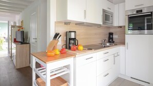 A modern kitchen with white cabinets, a wooden countertop, a sink, a coffee maker, and a Bosch oven. - Nice home in Süssau/Ostsee with sauna (Süssau/Ostsee)