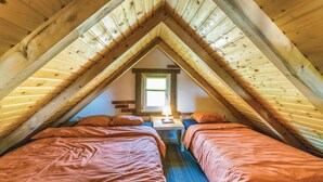 Een gezellig slaapkamer op zolder met twee bedden, een tafeltje en een raam met uitzicht.