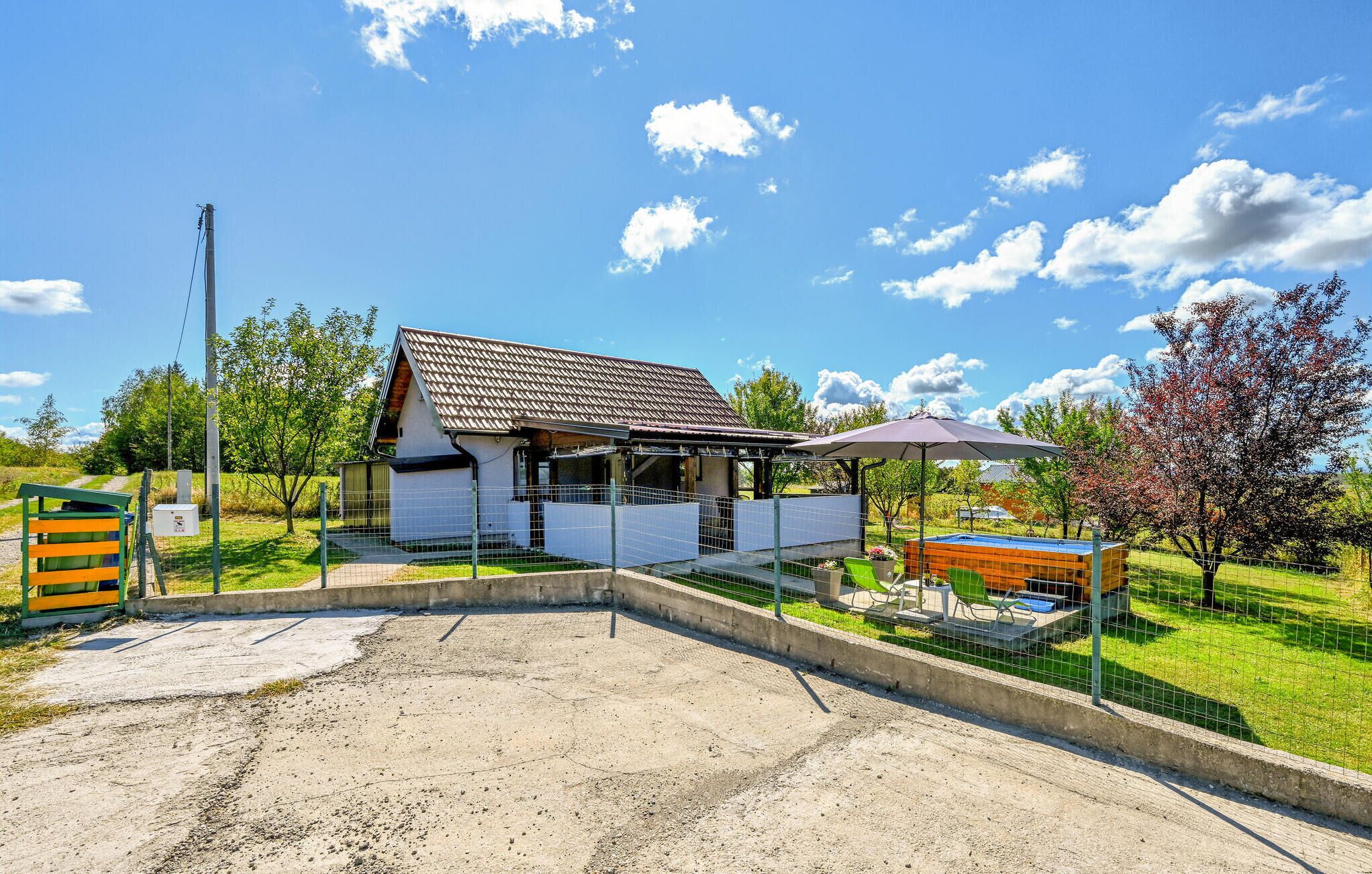 Une maison avec un jardin clôturé, une piscine et un patio couvert.