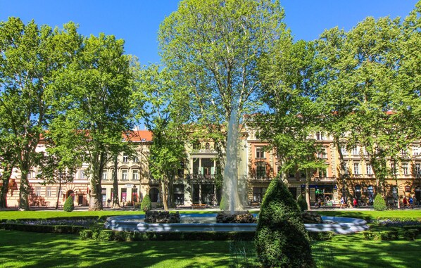 A large tree in a well-maintained garden with a fountain, surrounded by historic buildings with classical architecture. - Pet friendly home in Bratina (Bratina)